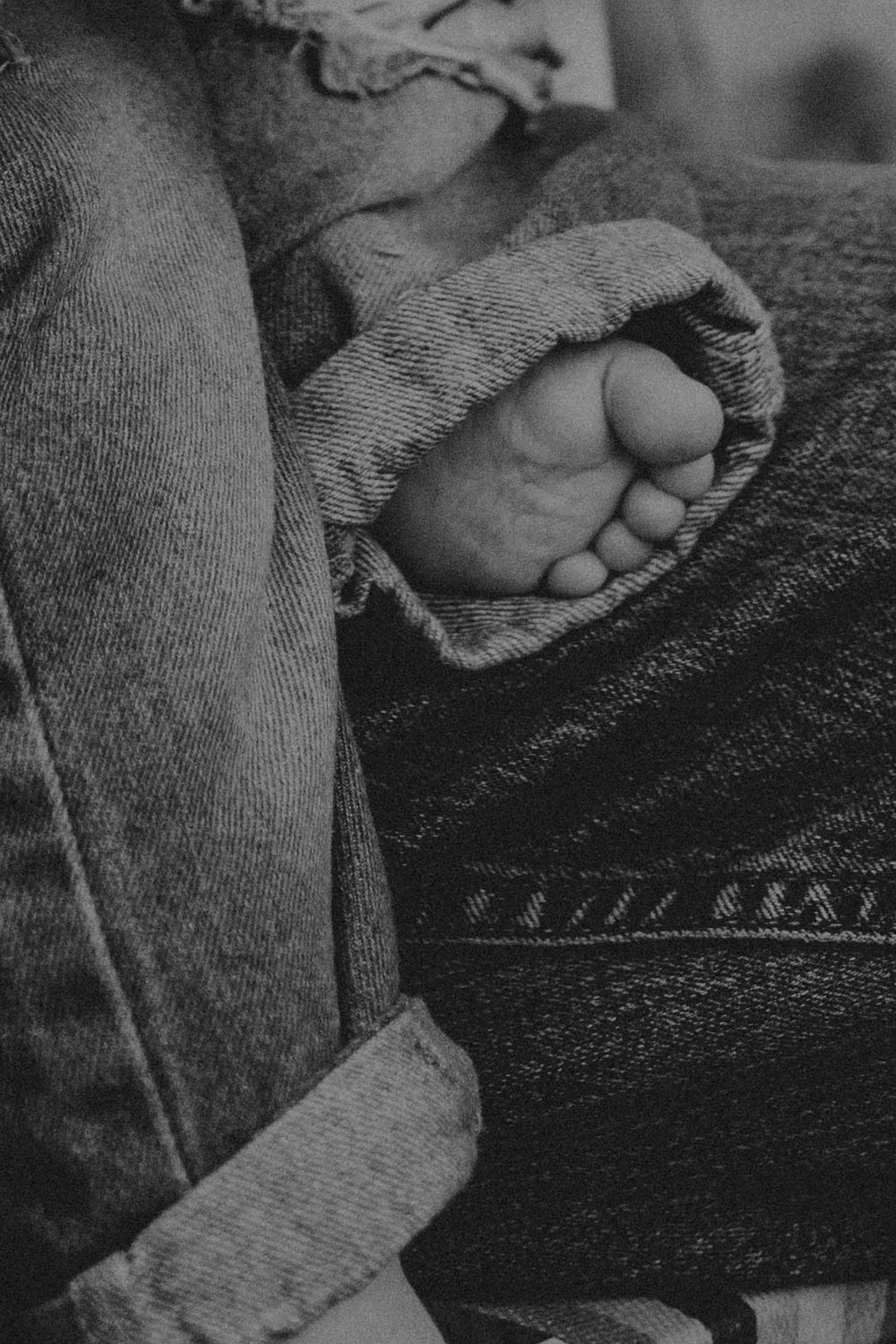 Close-up black and white image of tiny baby feet wrapped in soft knit fabric.