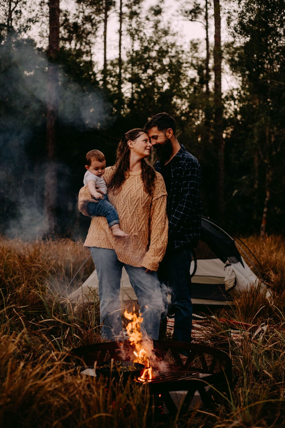 A cozy winter evening spent around a warm campfire in a wooded area at dusk with a rustic outdoor setting.