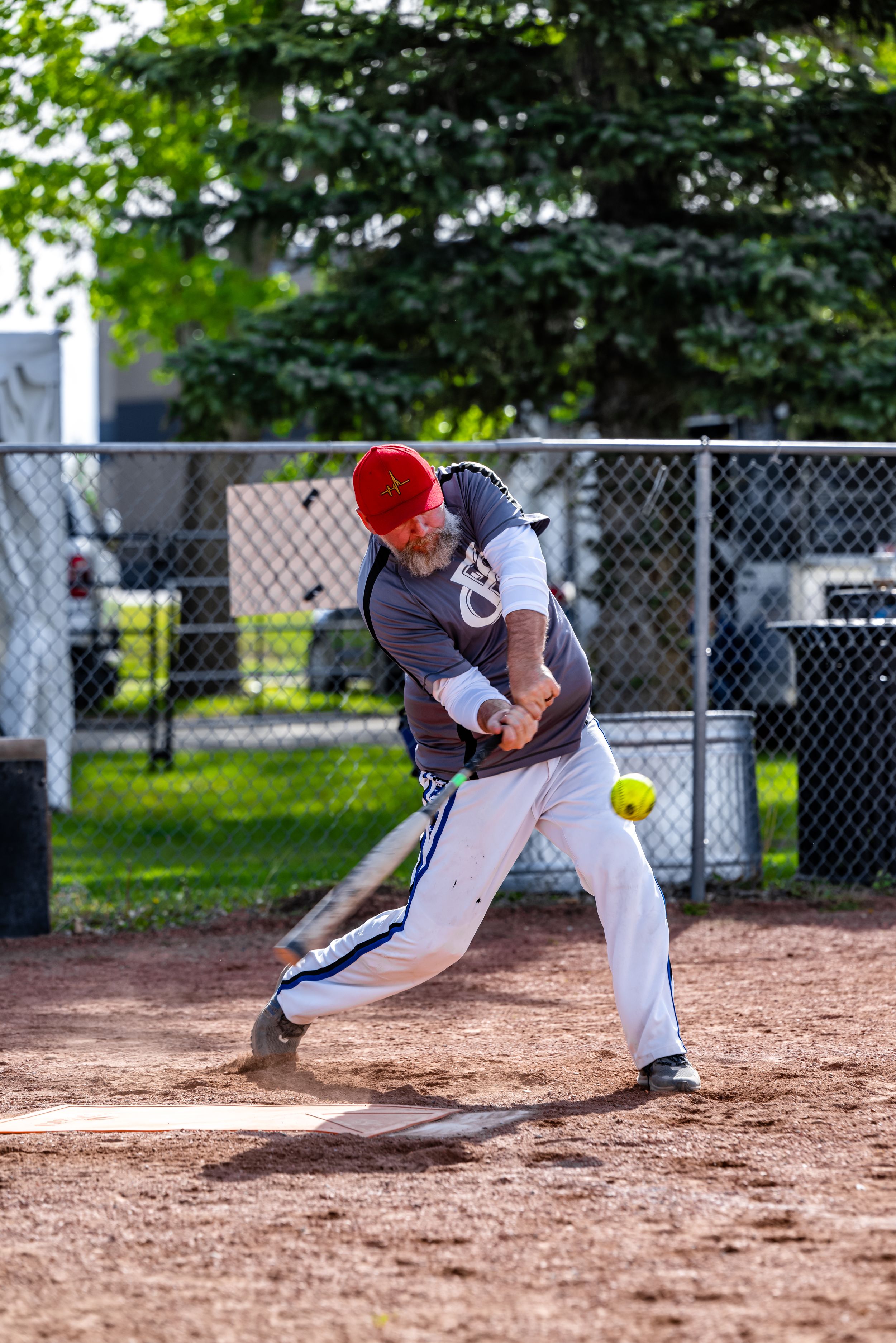 Softball player making a diving catch attempt on a dirt infield during a game.