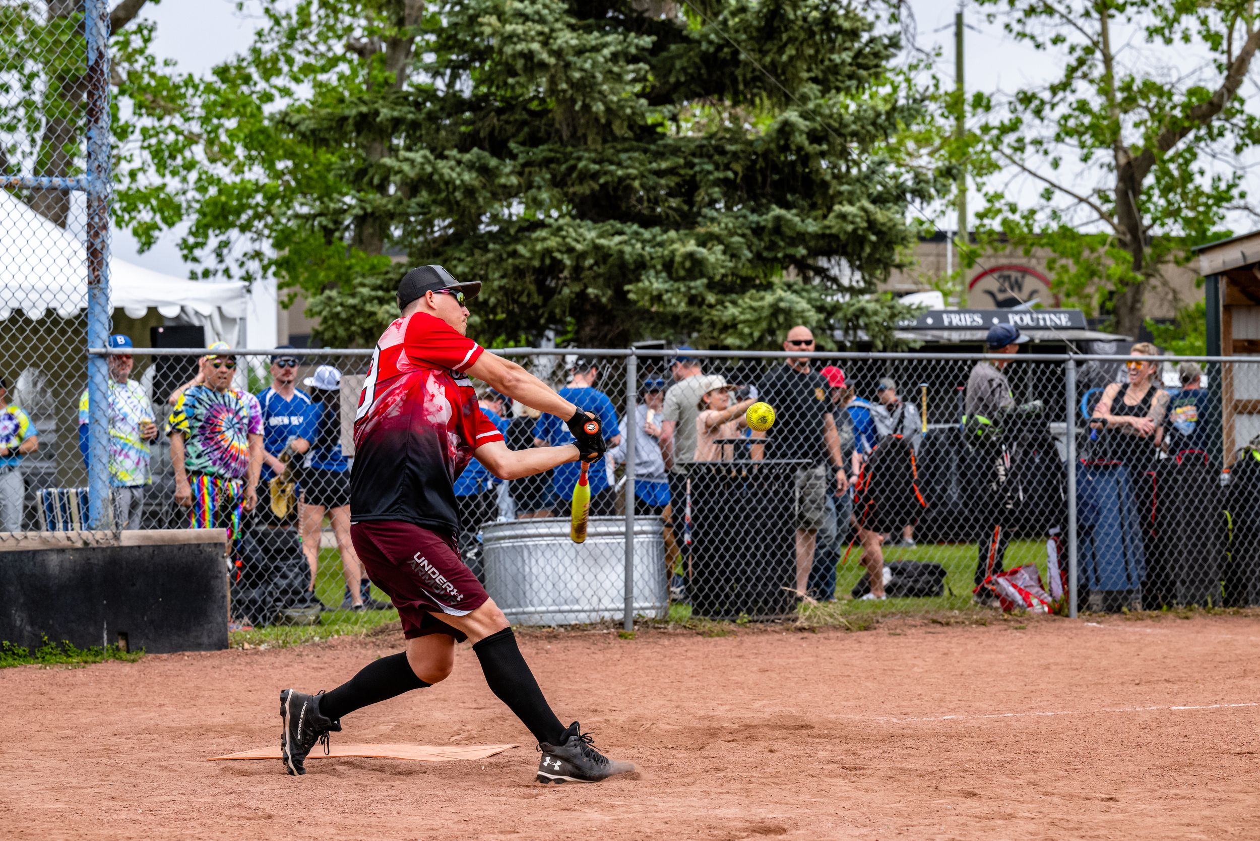 Baseball player slides into home plate during an intense game as spectators watch from behind the fence.