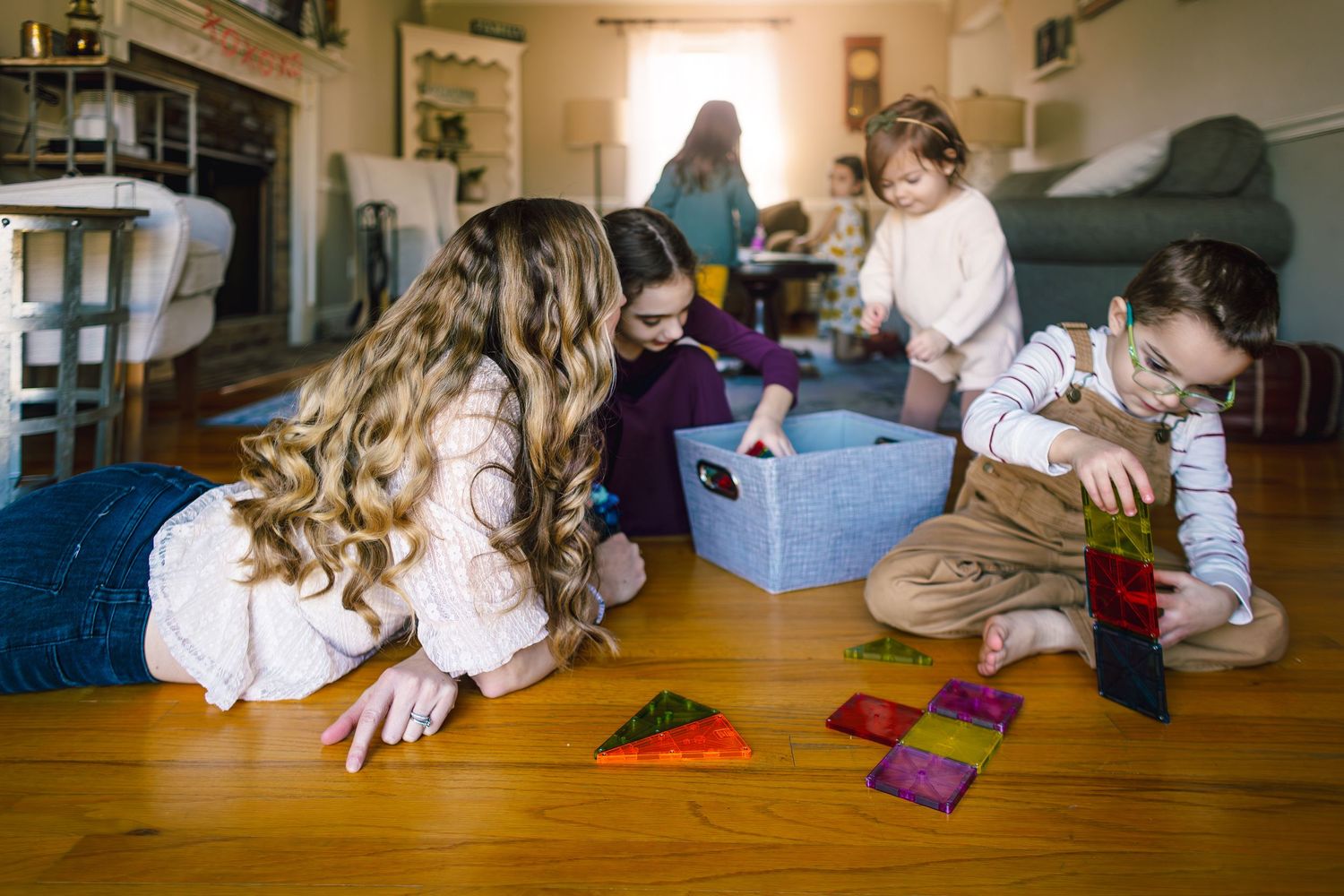 Children playing together with colorful cards on a hardwood floor in a cozy living room setting.