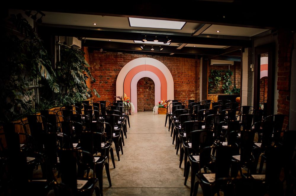 Rows of black theater seats face a stage in an empty auditorium with exposed brick walls and dim lighting.