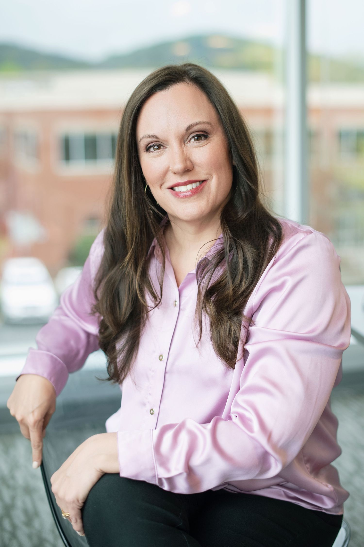 Professional headshot series of someone in a pink button-up blouse against a blurred outdoor background.