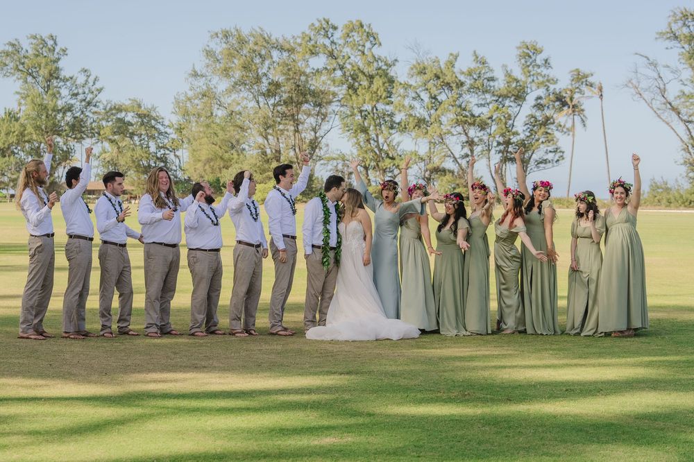 Wedding party poses together in a series of fun and playful photos on a sunny day in a grassy field.