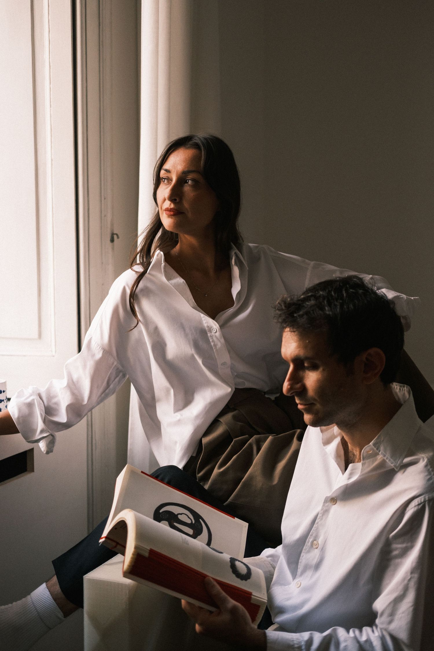 People in white shirts creating dramatic poses near window with natural lighting.