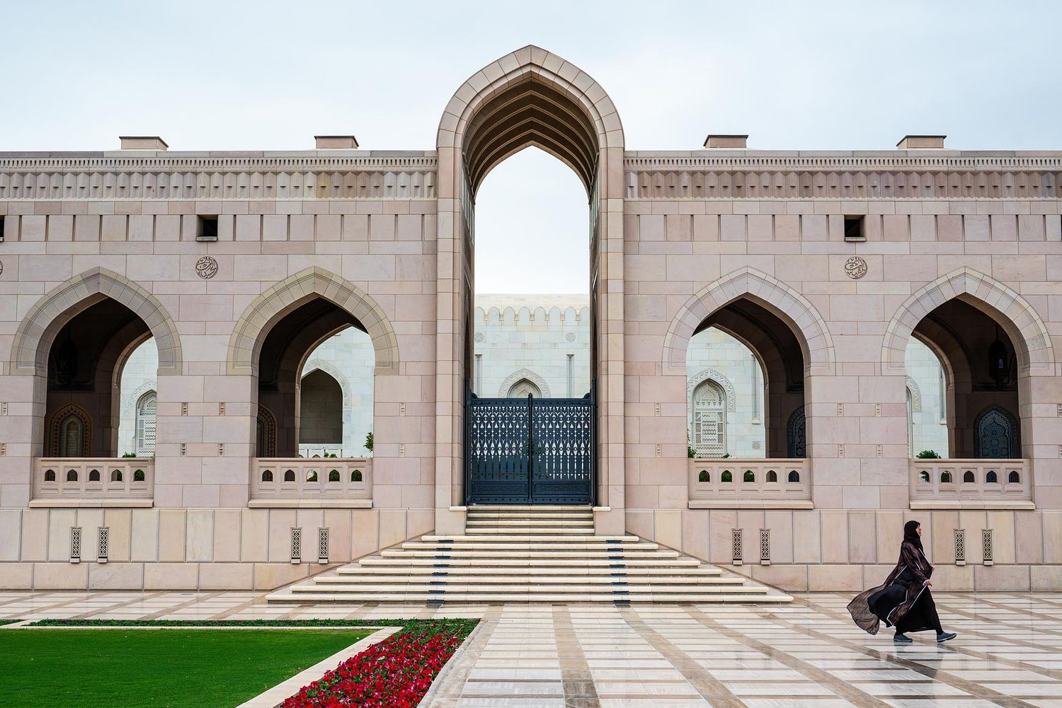 A person walks past the ornate arched entrance of Sultan Qaboos Grand Mosque in Muscat, Oman.