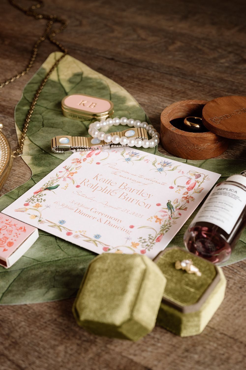 flat lay wedding details with the invitation, rings, jewelery, perfume and lord of the rings box