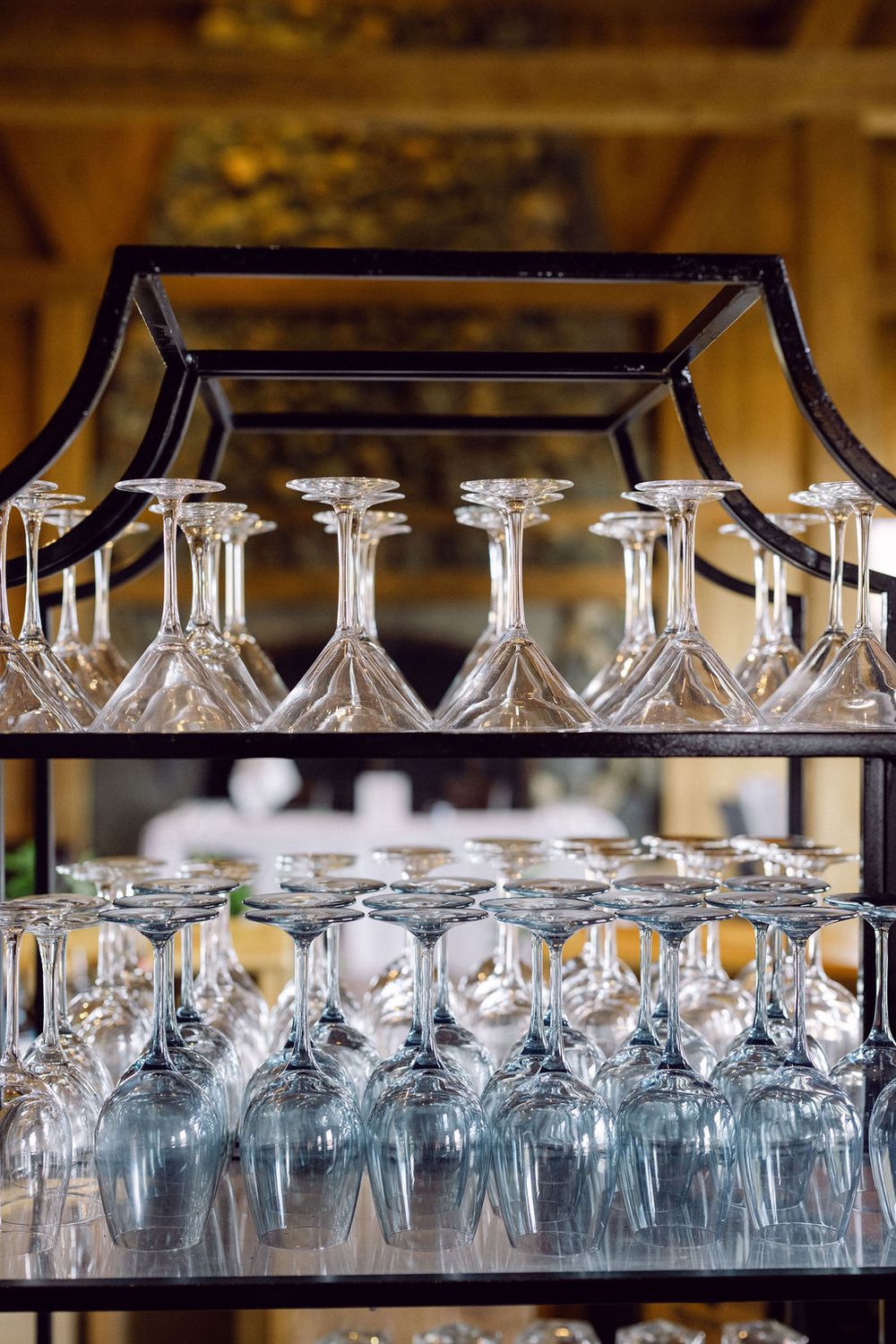 Crystal wine glasses arranged in neat rows on glass shelves with ambient lighting in an upscale bar or restaurant setting.