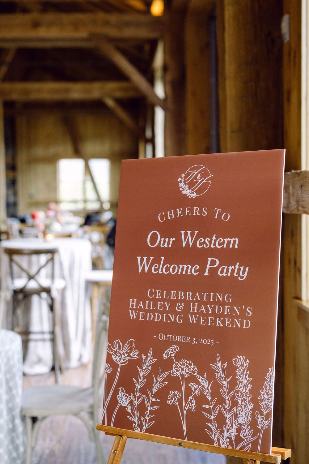 Rustic brown wedding welcome signs with floral designs displayed on wooden easels at a Western-themed celebration.