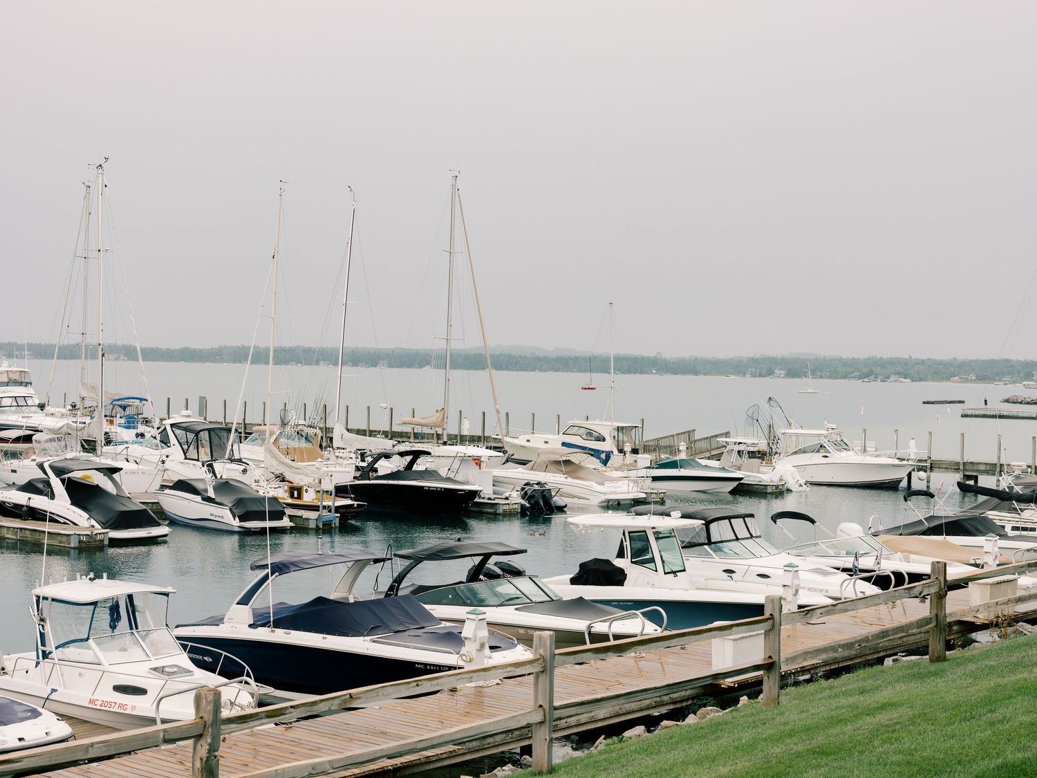 Aerial view of a marina with docked boats and waterfront buildings along a scenic coastline.