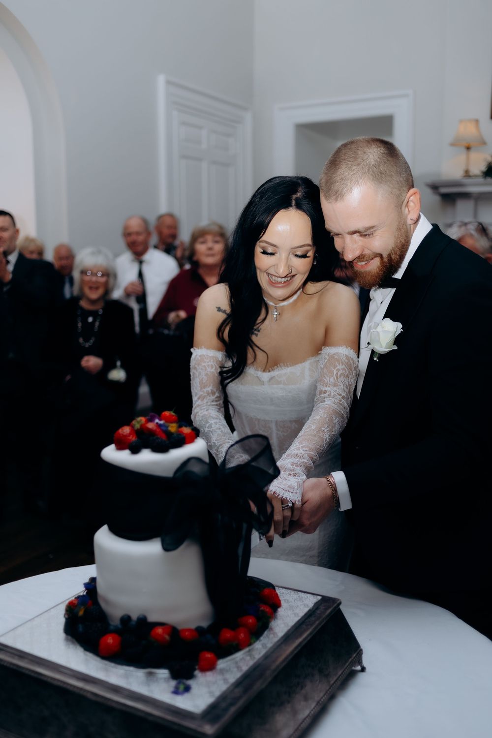 A wedding couple playfully smashes cake into each other's faces during their reception celebration.