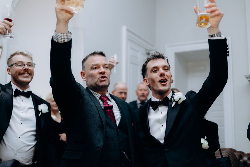 Wedding guests raise their glasses in celebration during a toast at an elegant indoor reception.