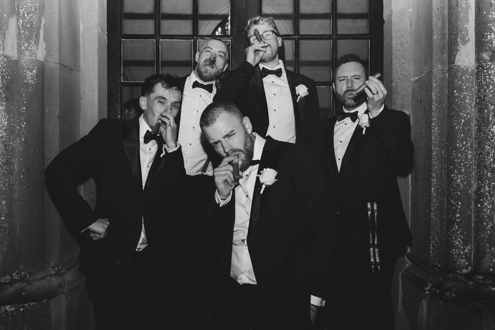 A formal black and white photograph showing a group of men in tuxedos gathered at an elegant event.