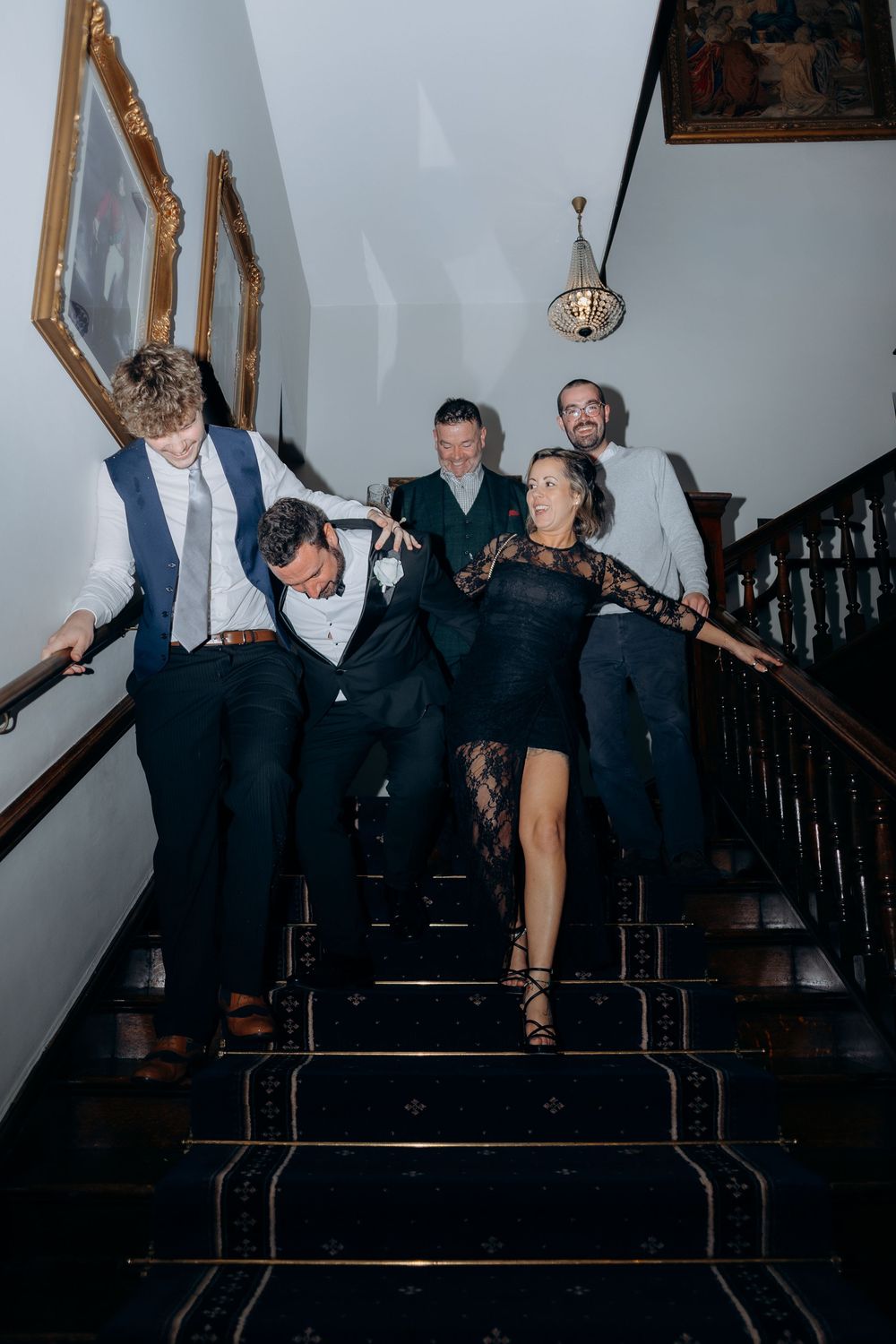 Guests dancing and having fun on a dark staircase at a formal event.