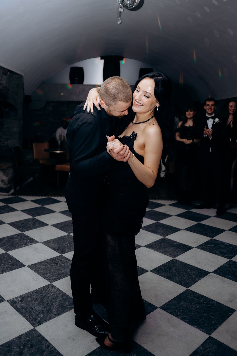 Couples dance on a black and white checkered floor during an elegant wedding reception.