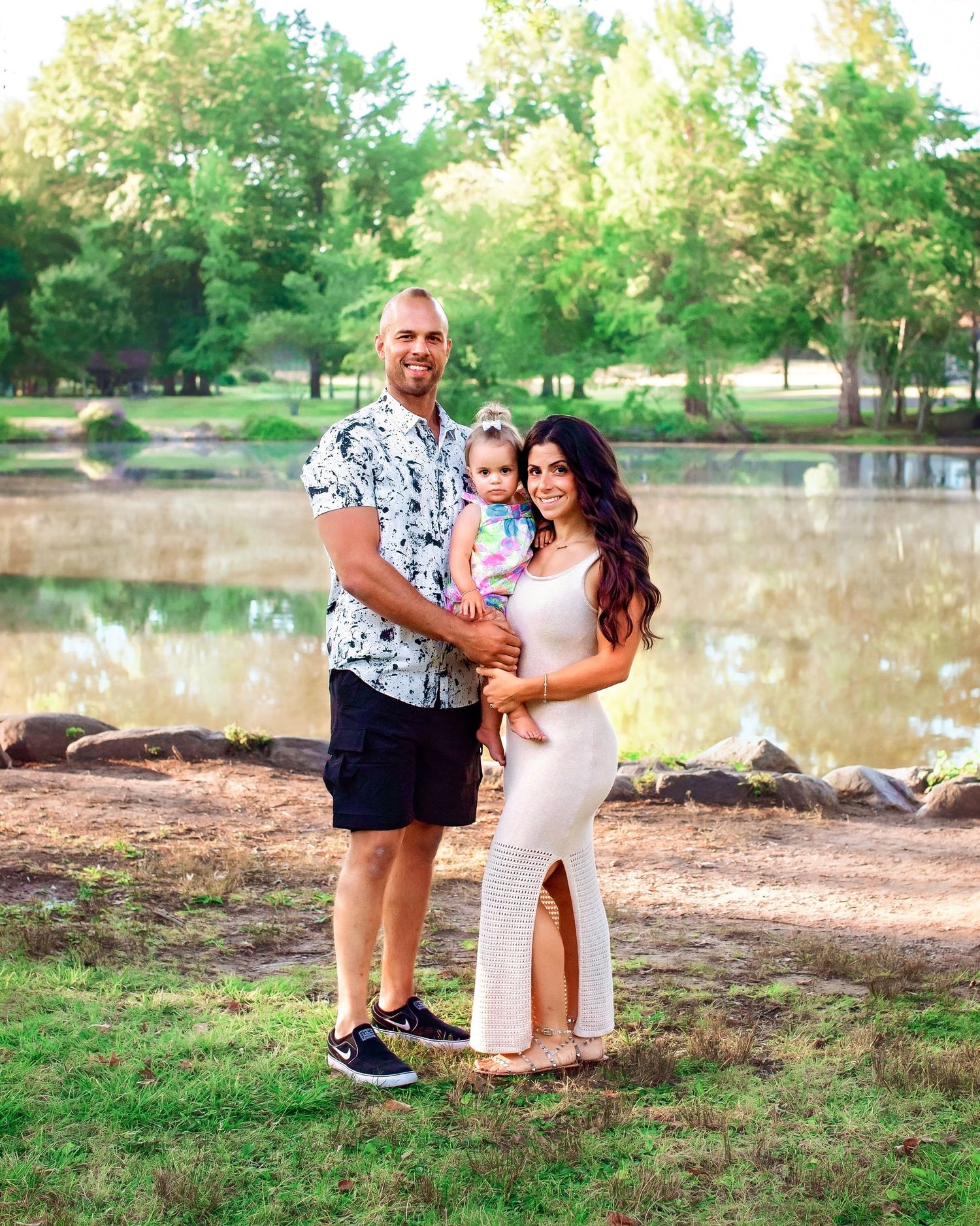 Parents and baby girl by beautiful lake near Westwood, NJ. Summer day colorful and sunny.