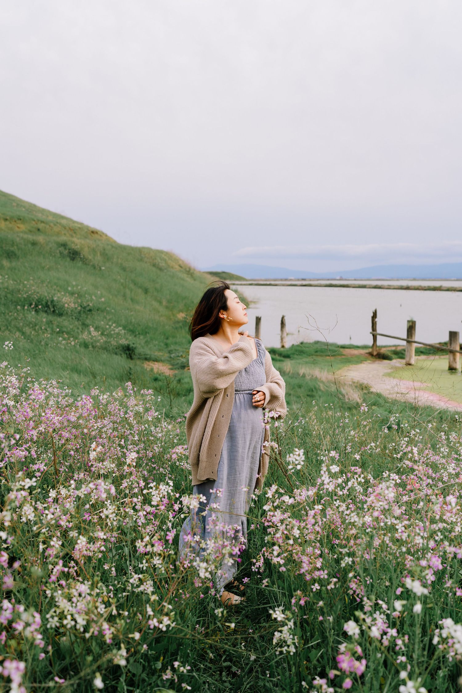 A tranquil seaside meadow filled with pink and white wildflowers against a misty coastal backdrop.