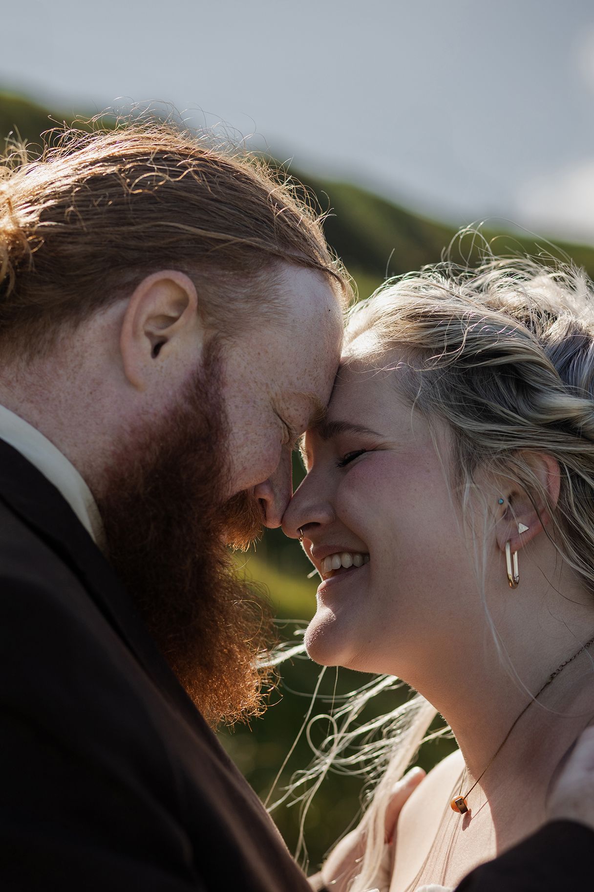 Couple embracing Irish weather during elopement with sunny Doolin ceremony and rainy Cliffs of Moher portraits
