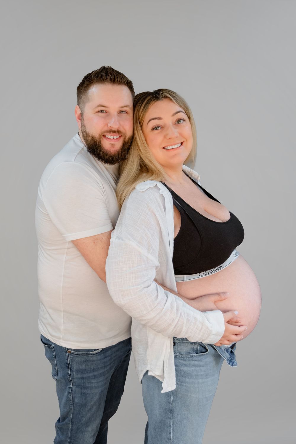 A series of five maternity photos showing a couple embracing against a gray backdrop.