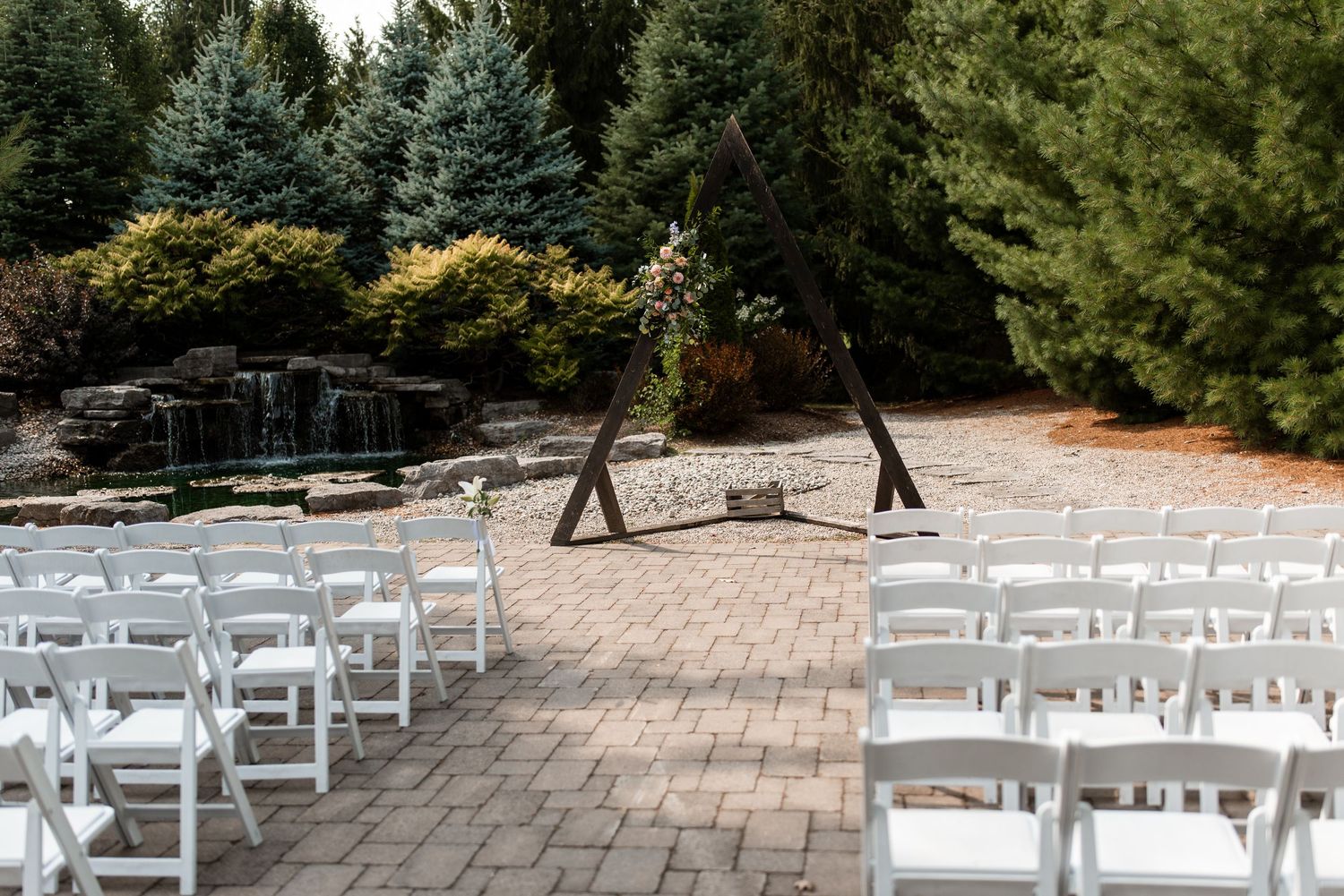 Outdoor Wedding Ceremony space at Strathroy Caradoc Sands Golf Club with stone patio surrounded by lush green trees and landscaping.