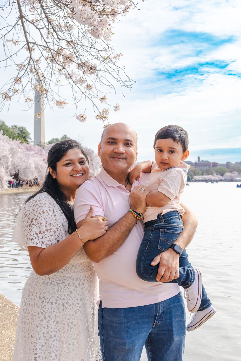 Family poses together near the Washington Monument with cherry blossoms in bloom.