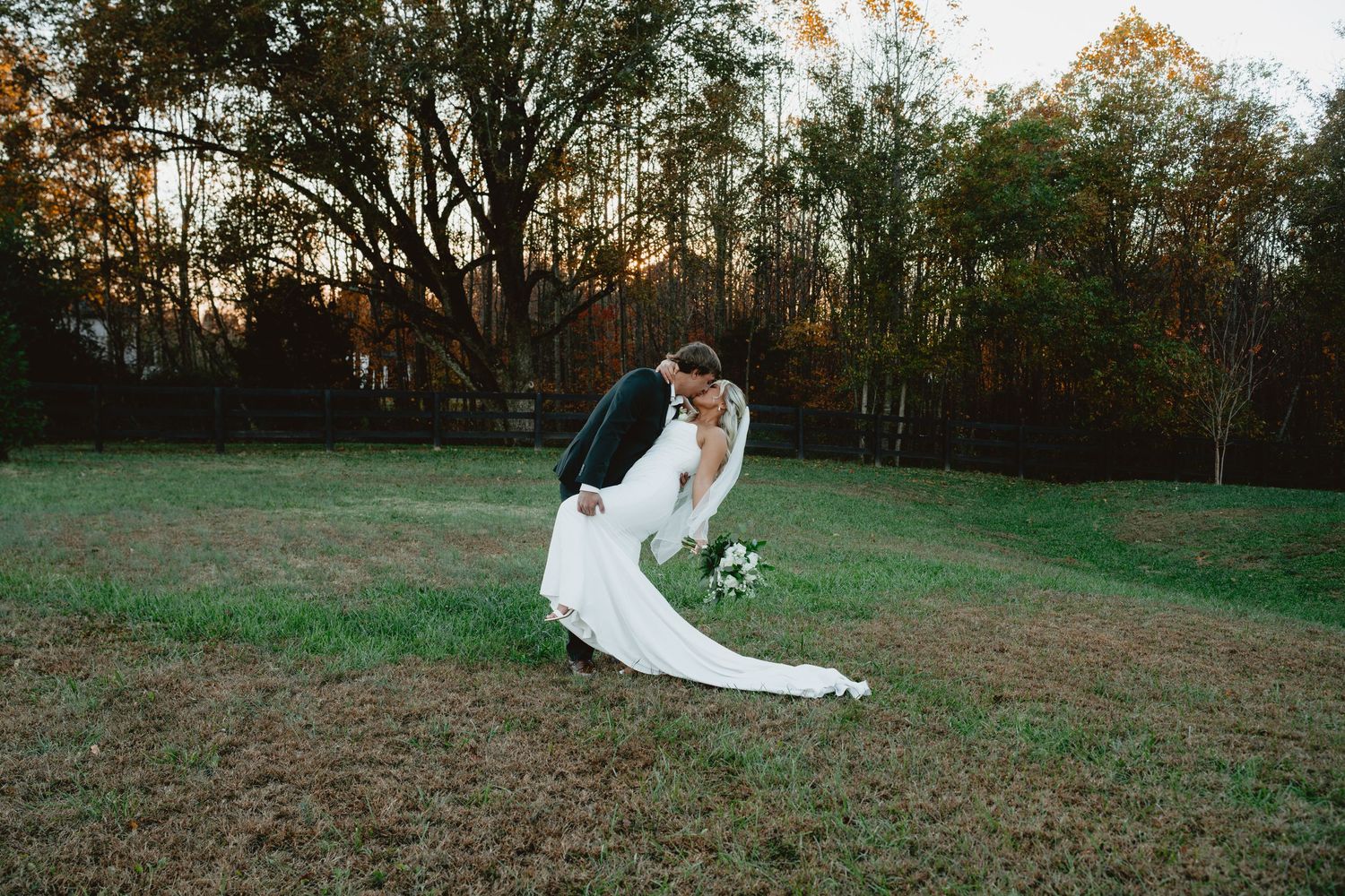 A rustic barn wedding reception features a white tiered cake and celebratory moments between guests.