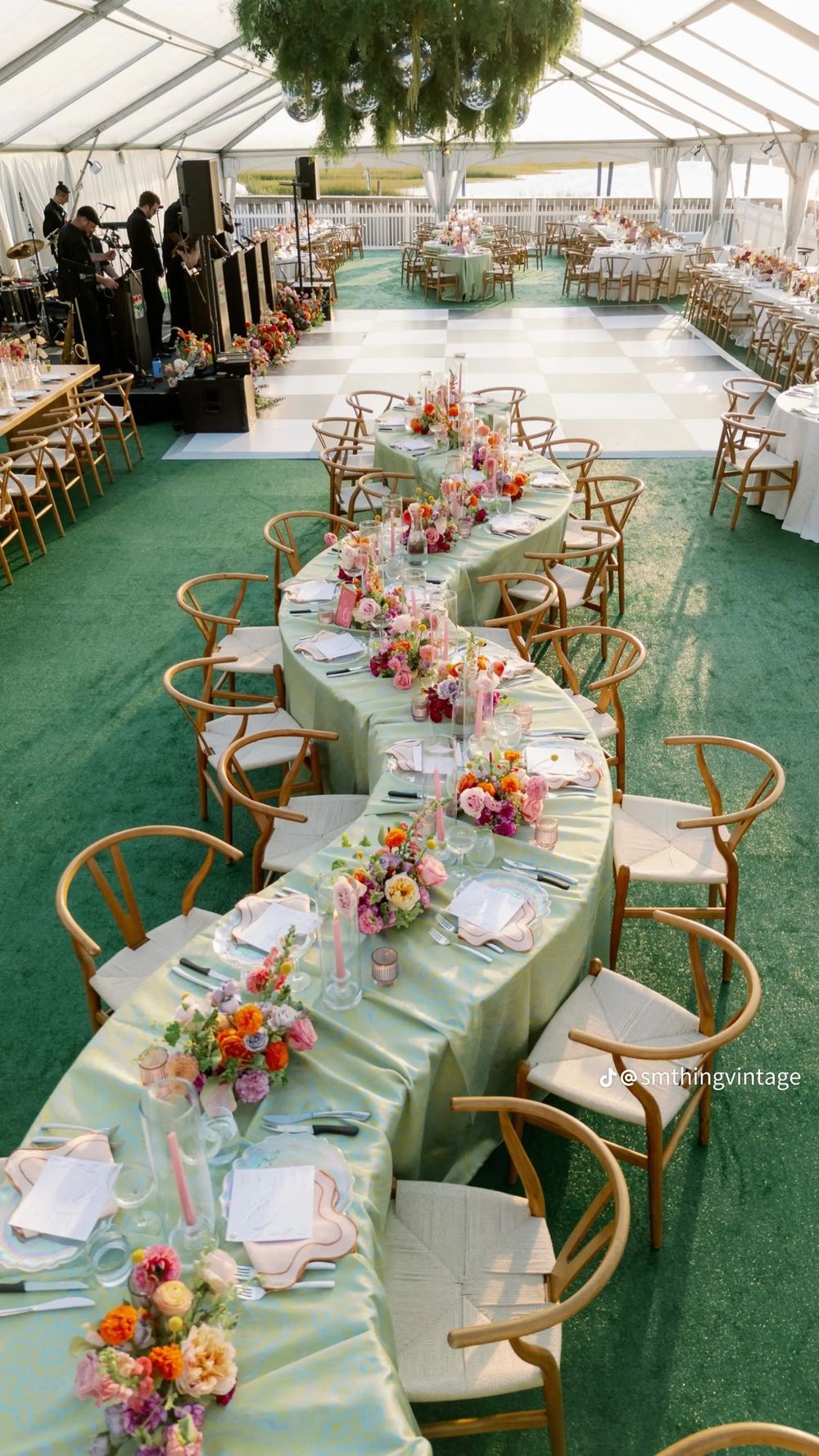 Serpentine wedding reception tables with sage green linens and colorful floral arrangements.