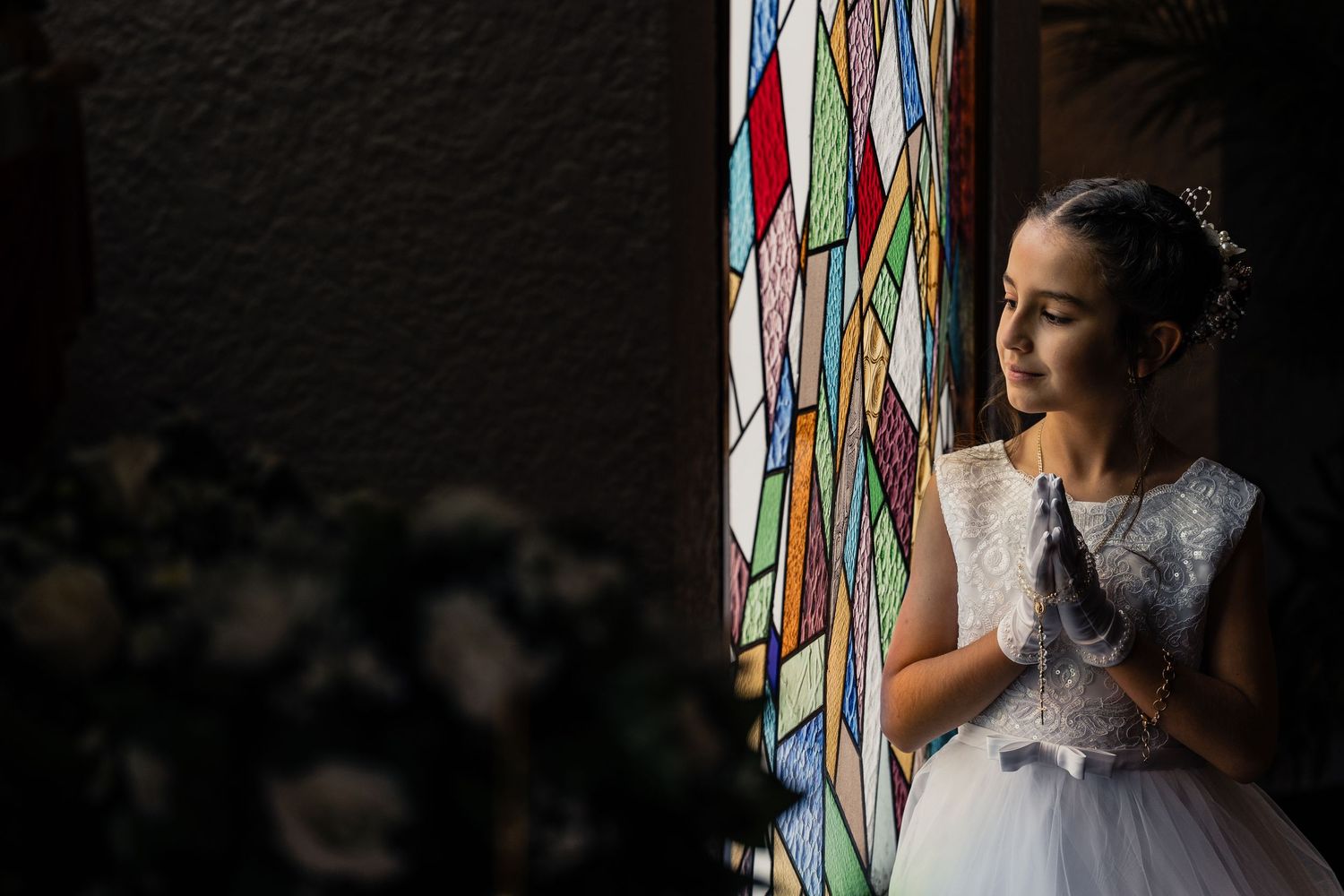A person in a wedding dress stands near colorful ribbons hanging from above, creating a whimsical scene.