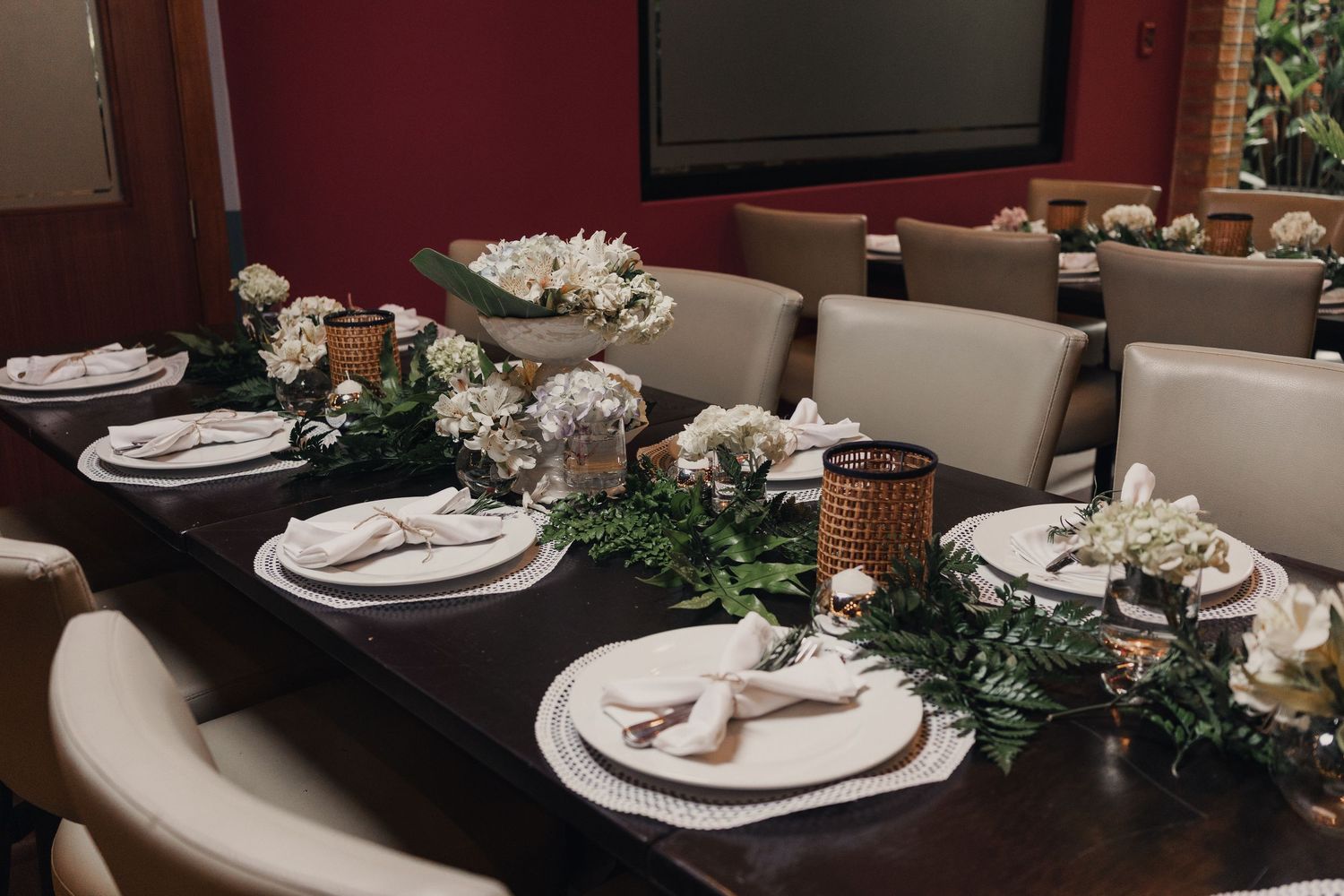 Elegant table settings with white plates, greenery garland, and candlesticks arranged for a formal dining experience.