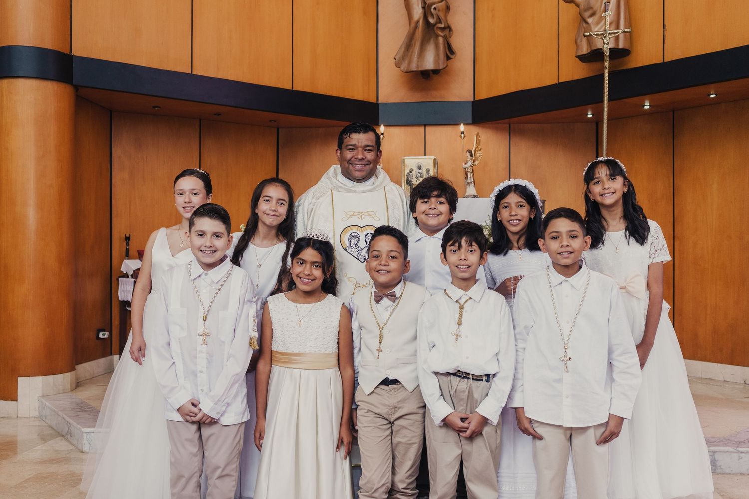 A group of people wearing white outfits stand together in a wood-paneled room for a formal occasion.