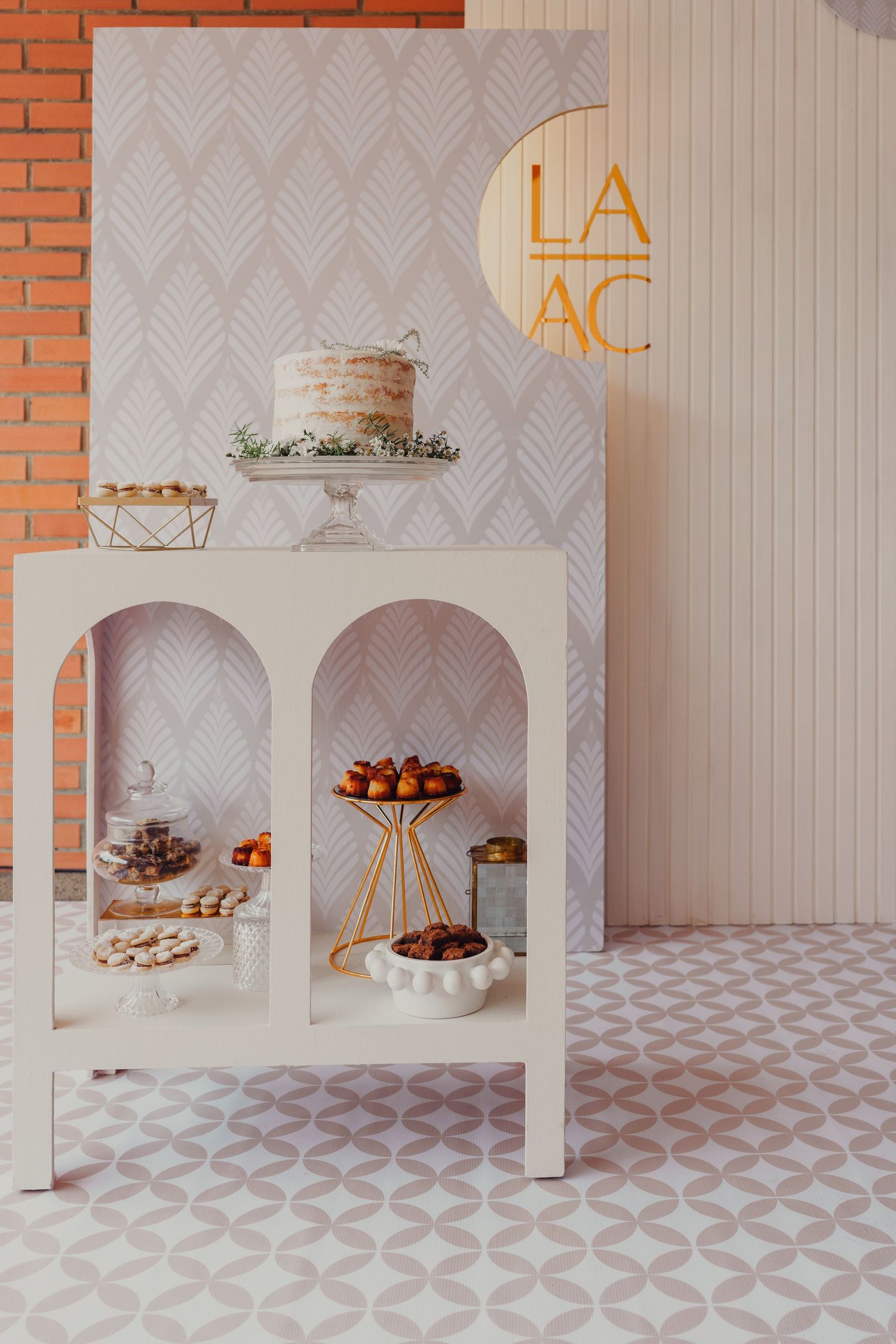 Modern white display setup with geometric patterns and desserts arranged on minimalist pedestals and platforms.