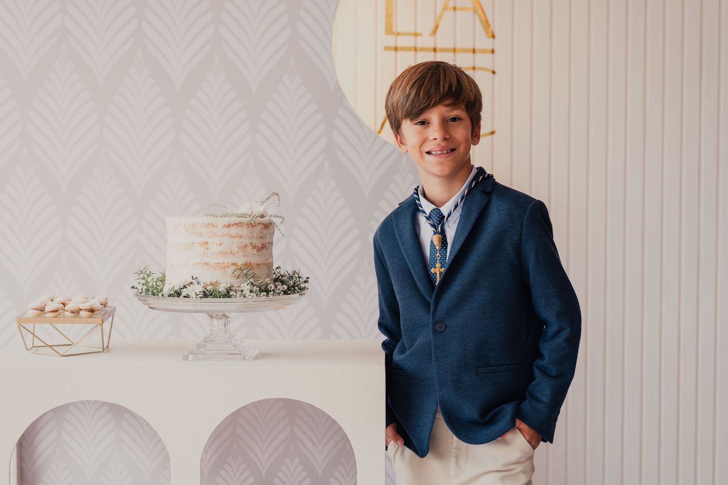 A person in a navy suit jacket stands near elegant white wedding cakes on display tables.