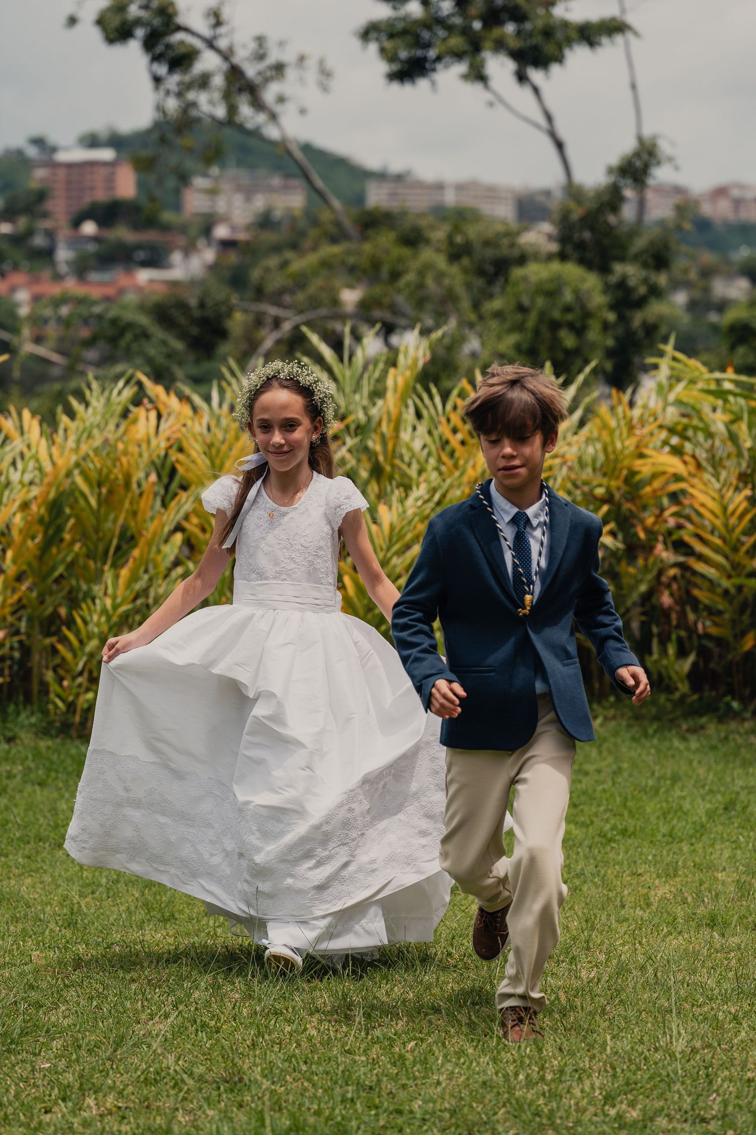 A couple runs playfully through a garden with the bride's white dress flowing in the breeze.