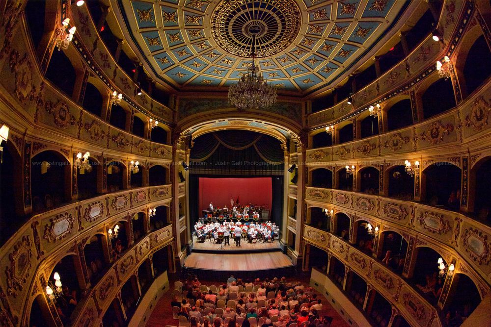Ornate theater interior showing decorated ceiling and multiple balcony levels with red seating.