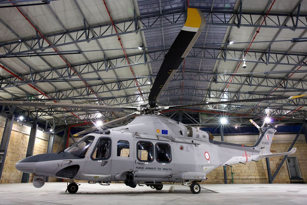 Military helicopters and aircraft displayed inside large maintenance hangar facility.