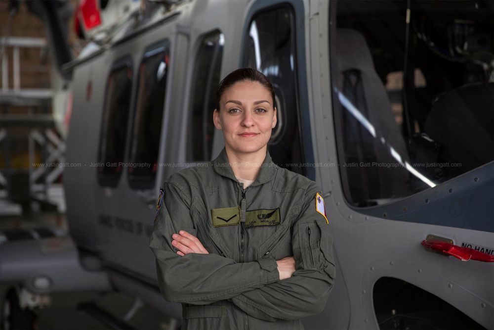 Military helicopter maintenance crew working on aircraft systems in a hangar.