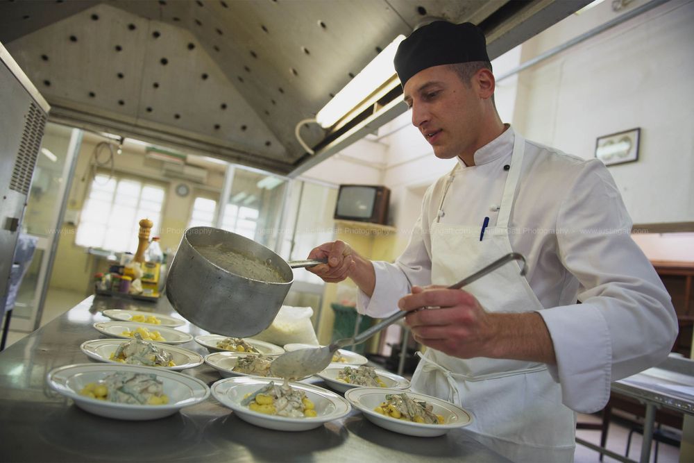 Chefs preparing multiple plates of food in a professional kitchen setting.