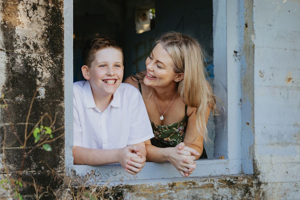 A tender moment between parent and child as they share laughter while sitting in a rustic window frame.