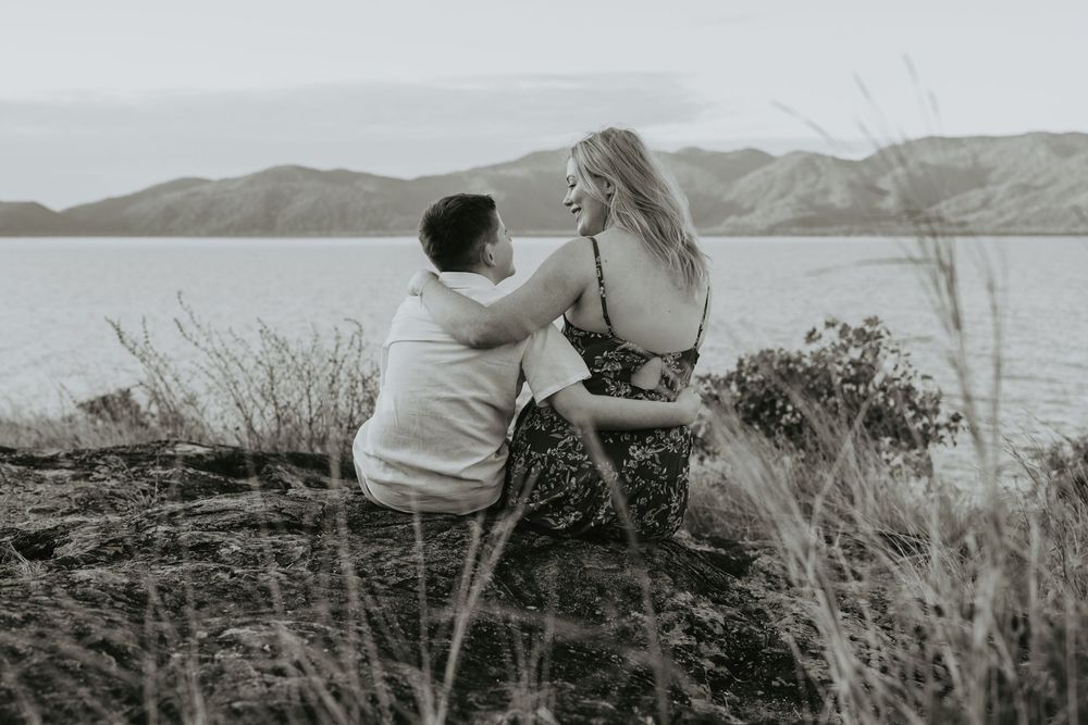 A black and white photo series showing someone photographing a scenic coastal landscape with mountains and water.