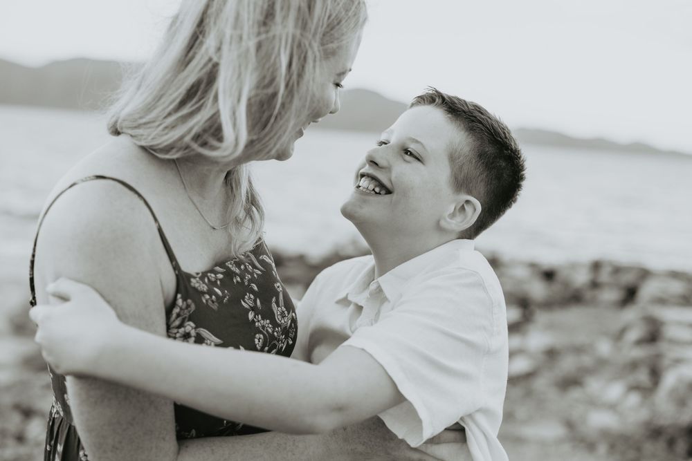 A romantic couple shares tender moments in black and white engagement photos on a beach.