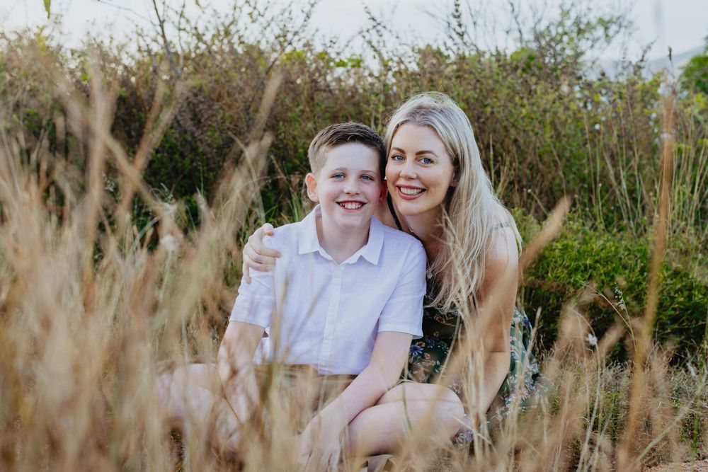 Couple sharing joyful moments together in a field of tall grass during golden hour.