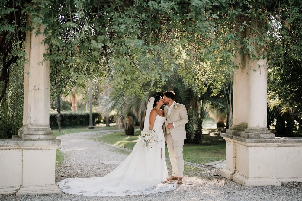 Bacio degli sposi sotto il portico nel giardino di Villa Nobel a Sanremo durante il servizio fotografico di matrimonio