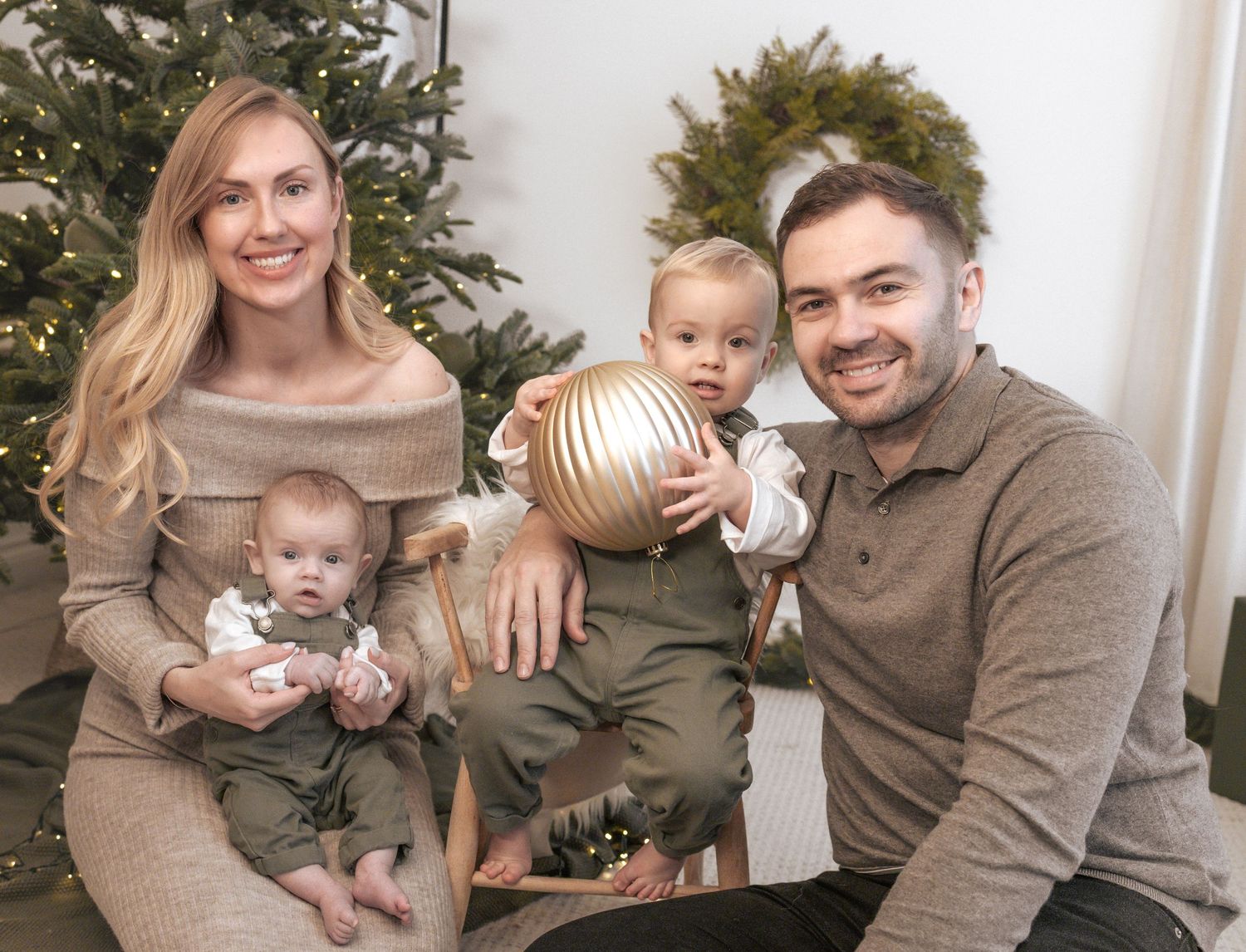 Family holiday portraits with baby in front of decorated Christmas tree. Photography in Buckinghamshire.