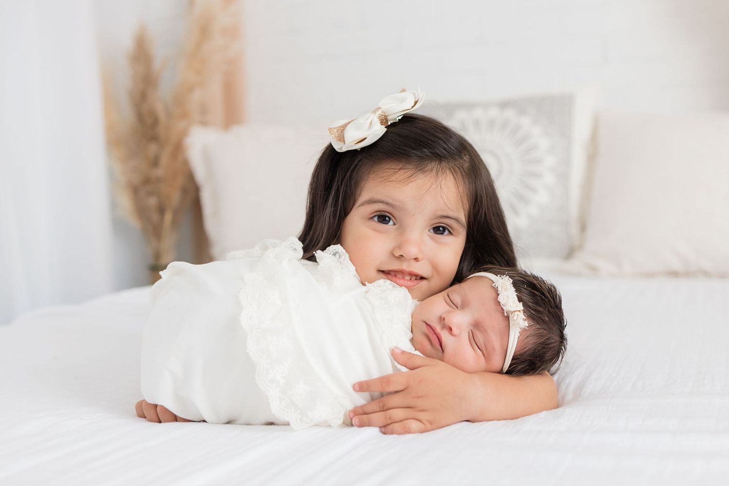 A sleeping newborn baby lies peacefully on white bedding with a small stuffed animal nearby.