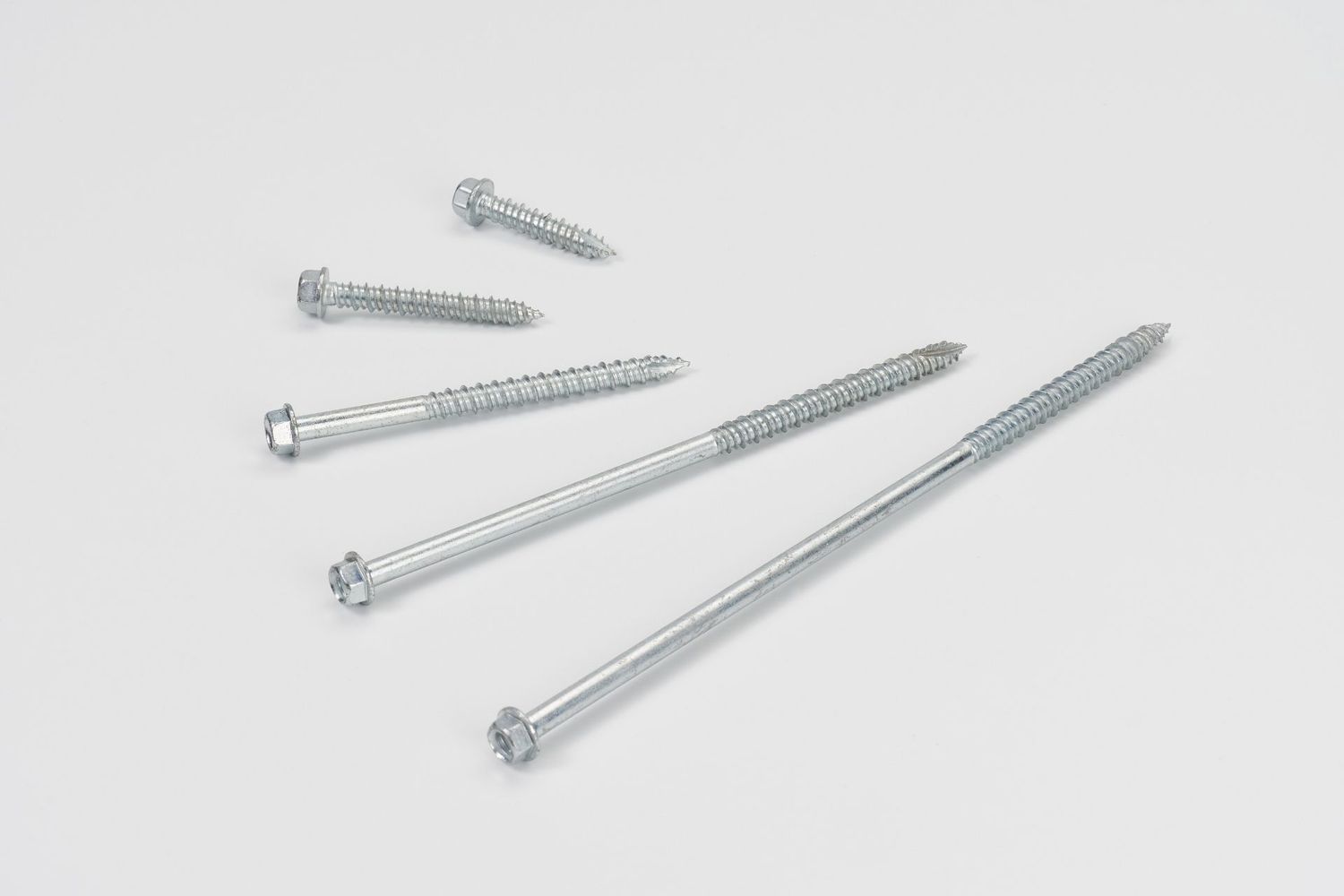 Four silver metal screws of varying lengths arranged in a row on a white background showing different sizes and threading.