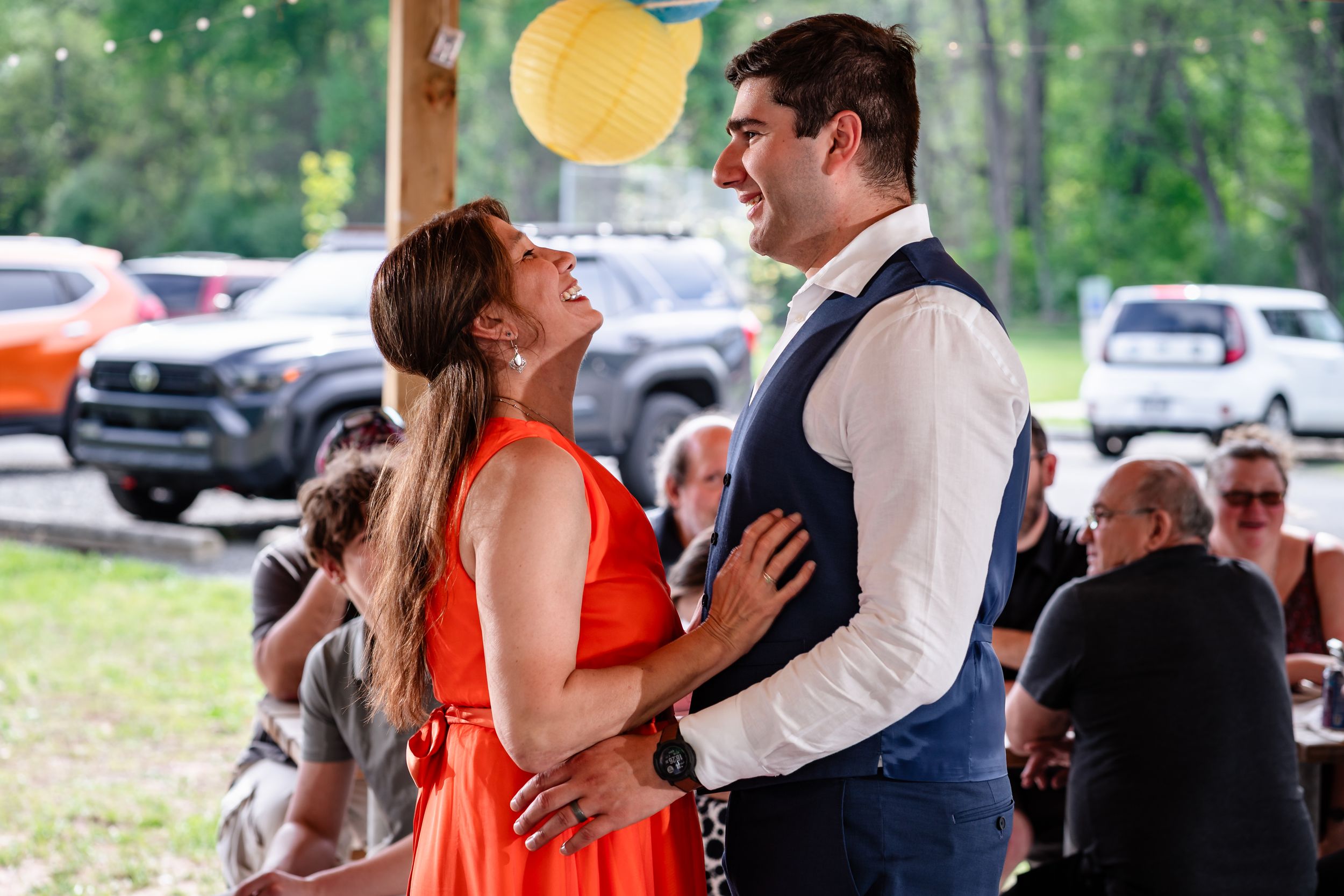 Couple sharing a joyful dance at an outdoor wedding reception under festive paper lanterns.