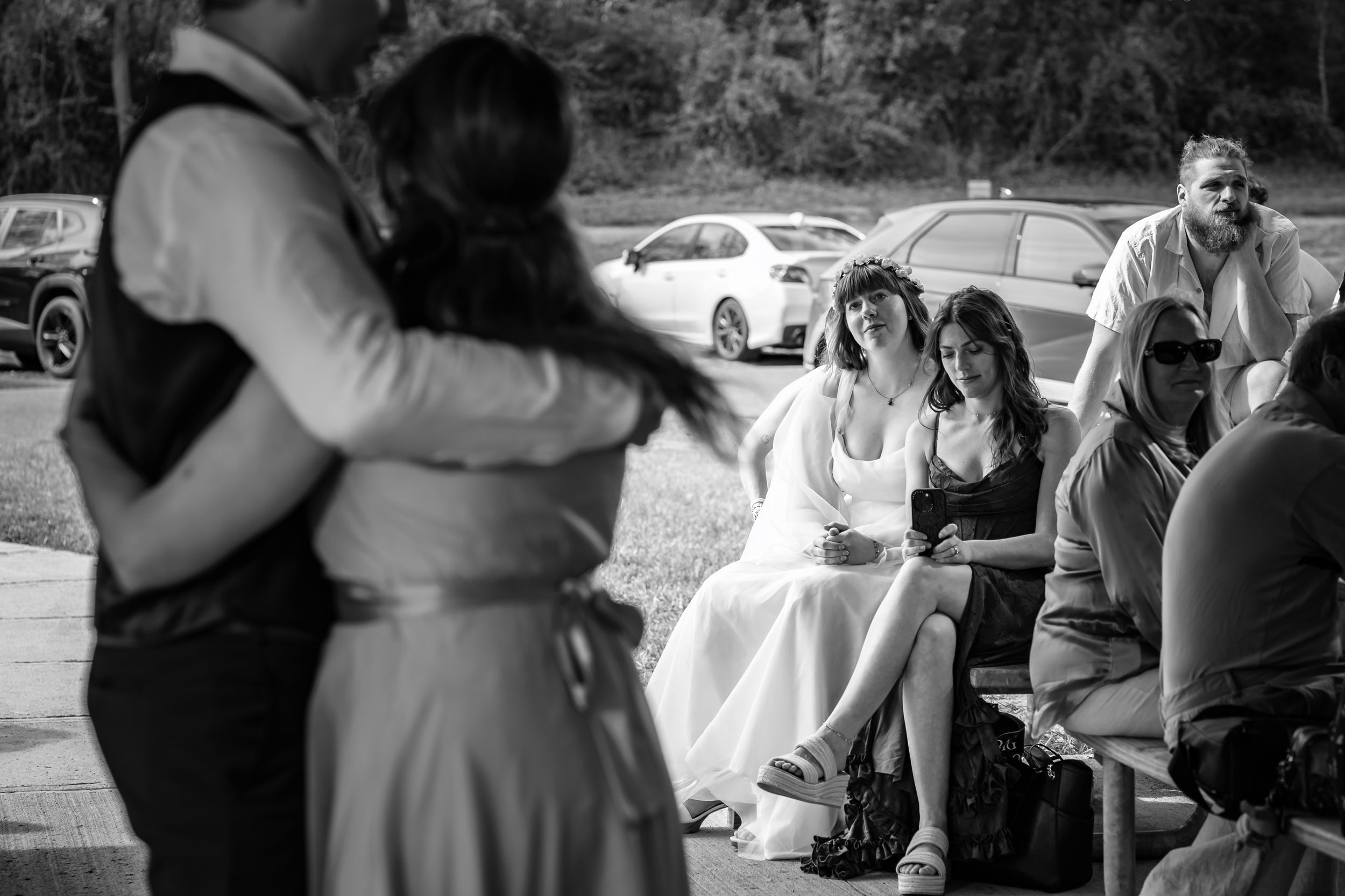 Black and white photo of wedding guests watching couple share first dance at outdoor reception.