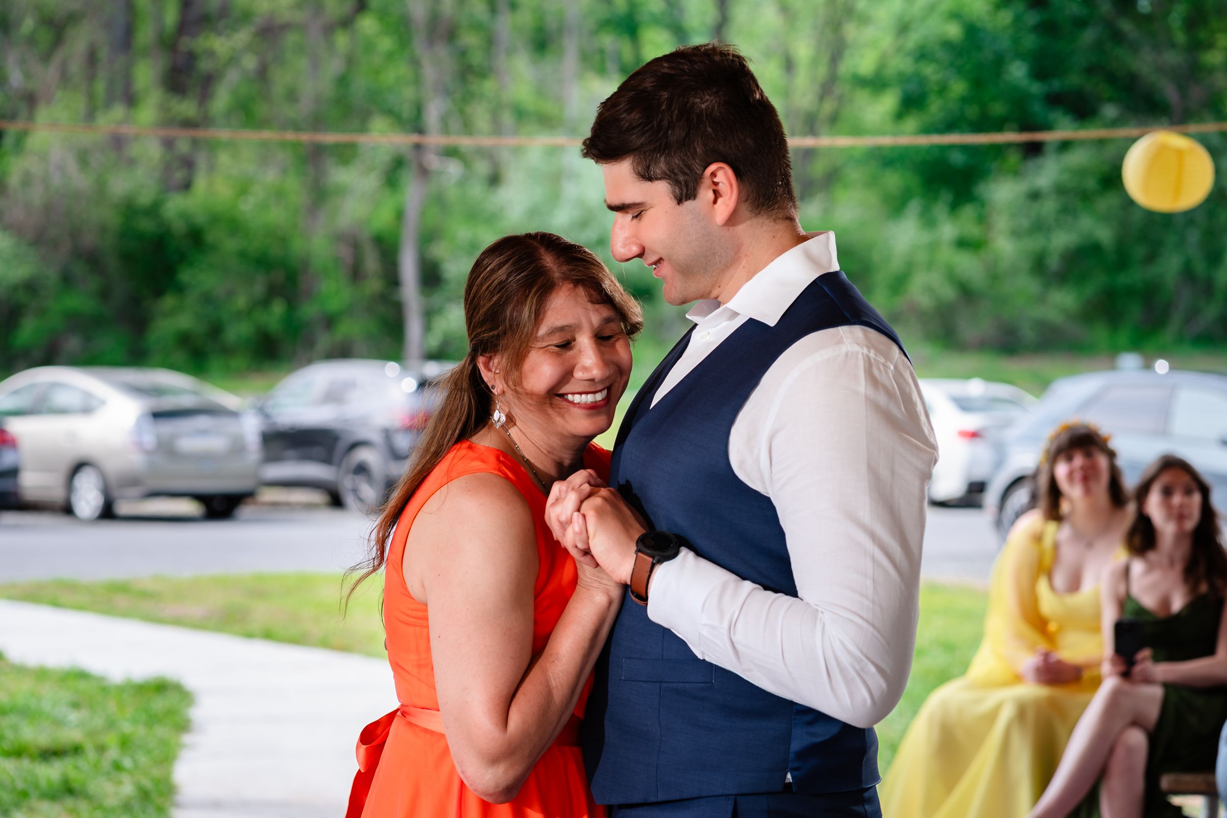 Couple shares a joyful dance outdoors at a sunny wedding reception.