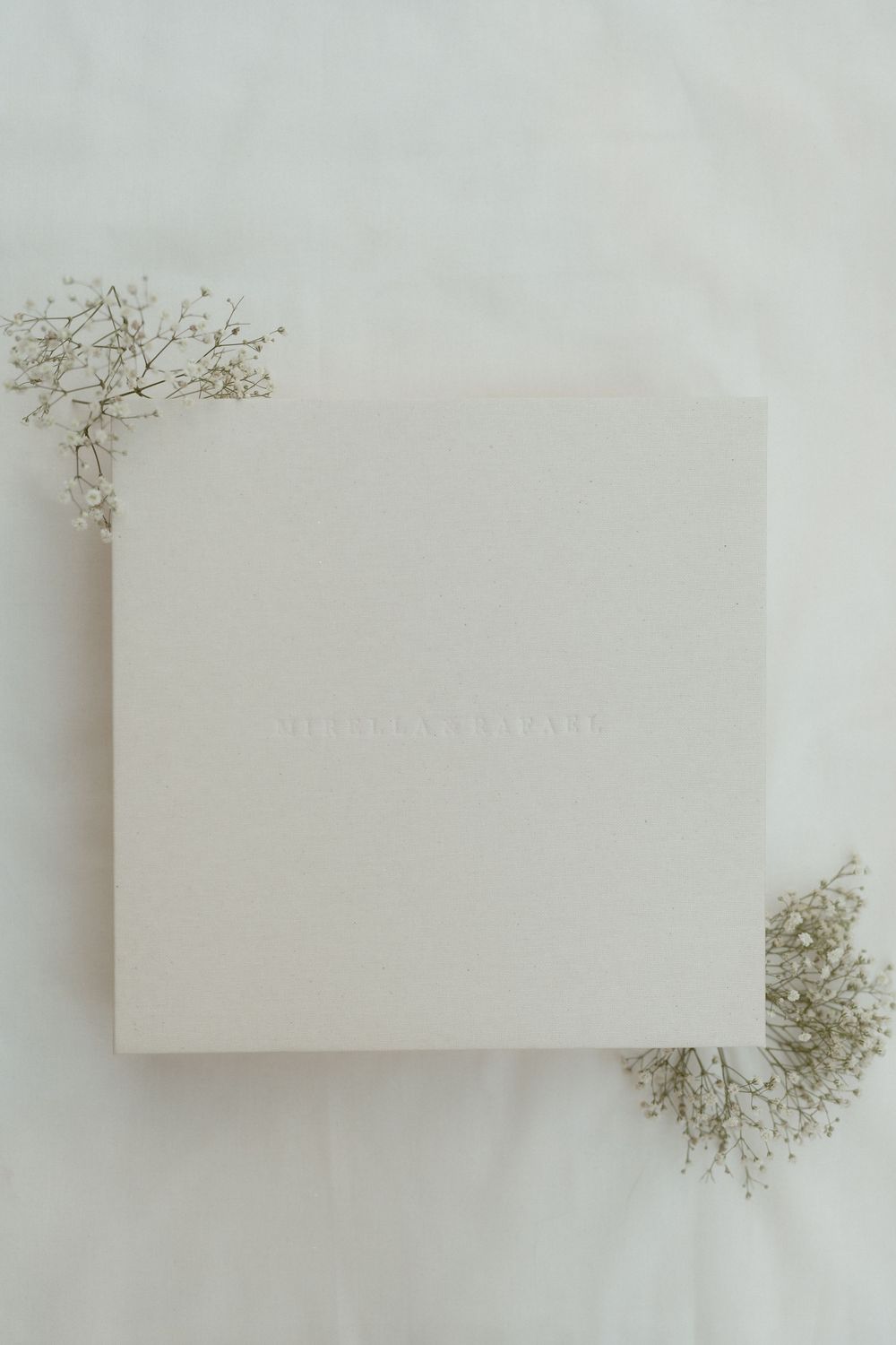 Minimalist white business cards arranged in a grid pattern with delicate dried baby's breath flowers on light background.