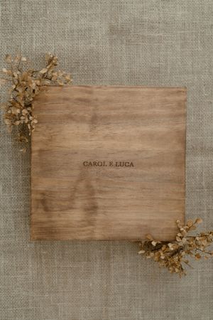 Four wooden place cards with dried flowers arranged in sequence on a linen background.